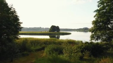 İnsansız hava aracı buğday tarlaları, ahşap kayık ve küçük ada üzerinde uçuyor. Yazın inanılmaz bir şekilde durgun olan Belarus gölüne doğru..