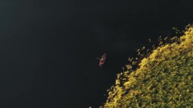 Üst görüntüde iki kişi kayıkla sakin bir yaz sabahı gölünde tatilin tadını çıkarırken görülüyor..