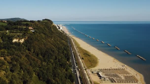 Drone panning acima colina verde com vista épica mar praia, revelando pequeno ensolarado baía cidade panorama de Pesaro, Itália. — Vídeo de Stock