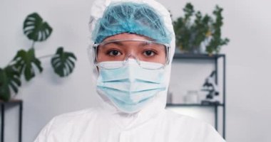 Hope koronavirüsle savaşıyor. Koruma giysisi içindeki çok ırklı kadın laboratuvar bilim adamı, aşı şişeleriyle tepsiyi gösteriyor..