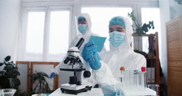 Professionele viroloog arts, wetenschapper in beschermingspak en schild die nieuw coronavirusvaccin maakt in kliniek lab. — Stockvideo