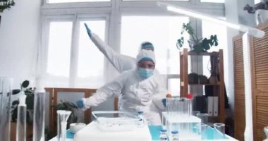 COVID-19 salgınının sonu. İki mutlu, heyecanlı kadın doktor, koruma giysileri içindeki bilim adamları kutlama dansı yapıyorlar..