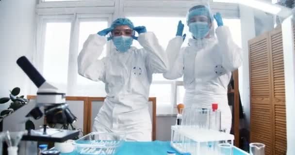 Vitória sobre o coronavírus. Diversão multiétnica feliz farmácia feminina médicos fazer dança divertida celebrando o sucesso, tirar máscaras fora — Vídeo de Stock