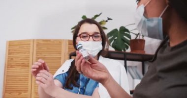 COVID-19 aşı konsepti. Virolog, eczacı kadın endişeli melez hastalara yeni bir ilaç şişesi gösterdi..