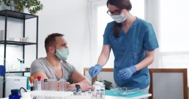 Aşı süreci. Mavi önlüklü genç hemşire kadın klinikteki erkek hastaya aşı aşısı yapıyor..