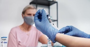 Aşı konsepti. Kıdemli hasta kadın, Coronavirus aşısı yapmak için şırınga kullanarak eldiven takıyor..