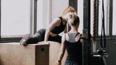 Genç, güzel, kızıl saçlı bir kadın, yoga salonunda geriniyor, sarışının kişisel koçu ağır çekimde fotoğraf çekiyor..
