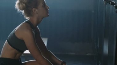 Genç, güzel, atletik sarışın kadın karanlık spor salonu soyunma odasında yalnız, yarışmadan önce kendini kaybolmuş ve stresli hissediyor..