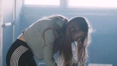 Güzel sarışın spor kadın karanlık spor salonunda dans ediyor. Ağır çekimde egzersiz yaptıktan sonra kendini harika ve canlı hissediyor..