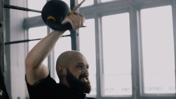 Atlétikai fiatal kemény fehér férfi edz, emelés kettlebell alatt funkcionális edzés nagy tornaterem lassított felvétel. — Stock videók