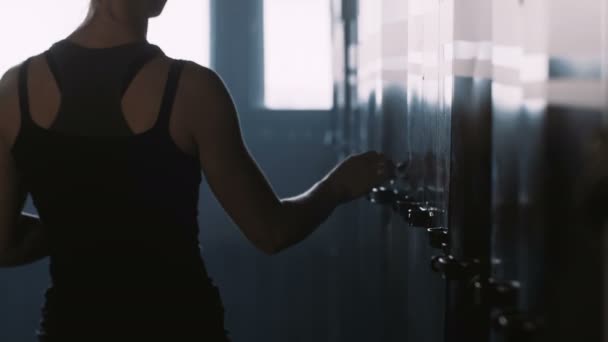Joven mujer rubia en forma hermosa poniendo cosas en el armario del gimnasio oscuro, superando la presión antes de las competiciones atléticas. — Vídeos de Stock