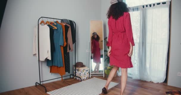 Trouver un look parfait. Heureux jeune blogueur de mode multiethnique attrayante femme dansant au miroir, essayant robe rouge sur. — Video