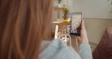 Video konferansı çevrimiçi. Omuz hizasında, mutlu kadın konuşmaları, akıllı telefon ekranında melez ırk dostlarına el sallamalar..