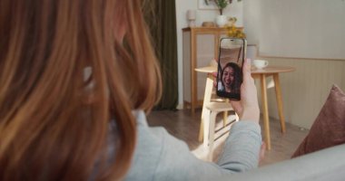 Video konferansı çevrimiçi. Omuz hizasında, mutlu kadın konuşmaları, akıllı telefon ekranında melez ırk dostlarına el sallamalar..