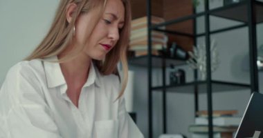 Mutlu odaklanmış 30 'lu yaşlardaki başarılı sarışın iş kadını modern ışıklı ofis masasında dizüstü bilgisayarla mesaj yazıyor..