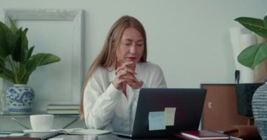 Ciddi şekilde odaklanmış başarılı 30 'lu yaşlarda sarışın patron iş kadını modern ofis masasında dizüstü bilgisayar kullanarak çalışıyor..