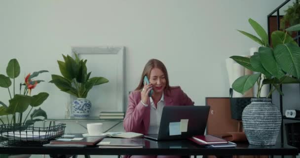 Занят на работе. Счастливые успешные 30-х блондинка босс бизнес-женщина работает в офисе с помощью ноутбука, разговаривая по мобильному телефону. — стоковое видео