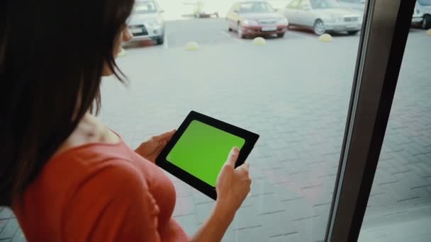 Mujer parada junto a la ventana y usando una tableta. pantalla verde — Vídeos de Stock