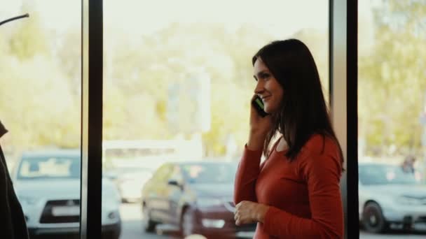 Una giovane donna parla al telefono vicino alla finestra nel caffè — Video Stock