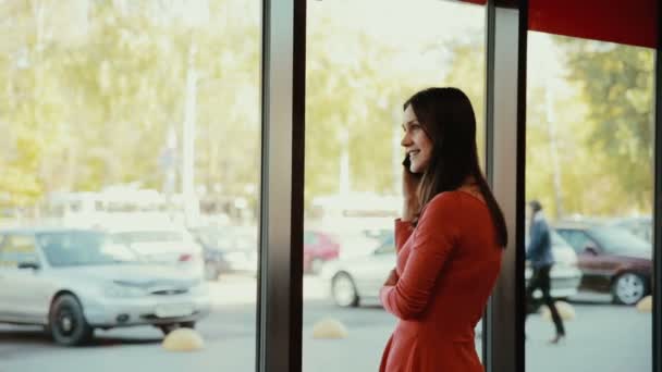 Een jonge vrouwen gesprekken over de telefoon in de buurt van het venster in café — Stockvideo