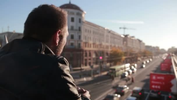 El hombre se para en un puente y muestra la ciudad — Vídeos de Stock