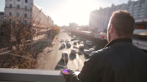 El hombre mira el tráfico en la ciudad al atardecer — Vídeo de stock