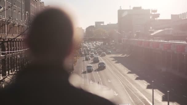 El hombre mira el tráfico en la ciudad al atardecer — Vídeo de stock