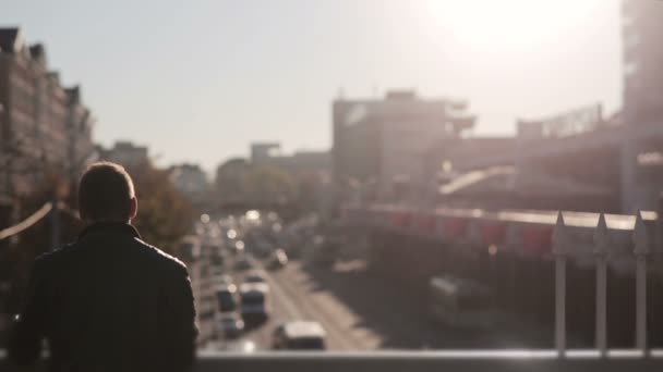 Mann sieht sich den Verkehr in der Stadt im Sonnenuntergang an — Stockvideo