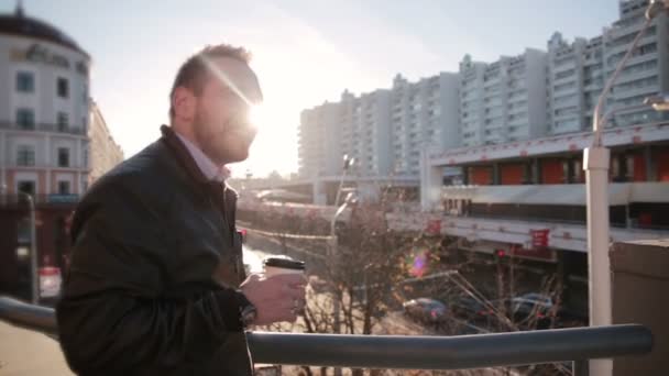 El hombre mira el tráfico en la ciudad, bebiendo café — Vídeos de Stock