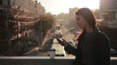güzel kız bir smartphone bir şehir köprüsü üzerinde kullanır.