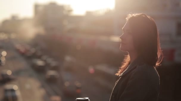 Красивая женщина пьет кофе на городском мосту — стоковое видео