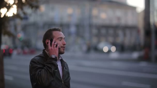 Młody mężczyzna rozmawia przez telefon na ulicy — Wideo stockowe