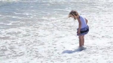 Küçük kız sahilde dalgalar ile oynarken