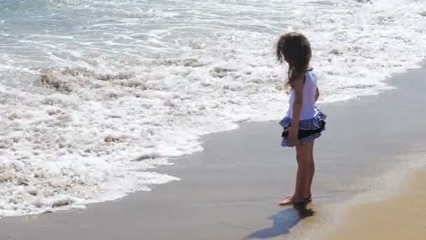 Liten flicka spelar med vågor på stranden — Stockvideo
