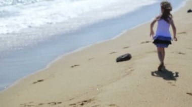 Küçük kız sahilde dalgalar ile oynarken