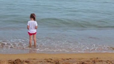 Küçük kız sahilde dalgalar ile oynarken