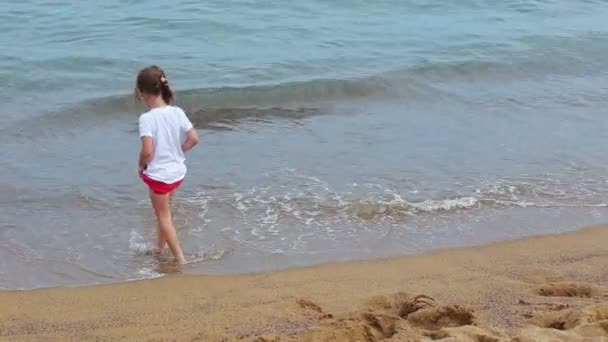 Niña jugando con olas en la playa — Vídeo de stock