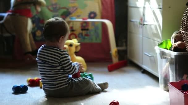 Маленький милий хлопчик грає з іграшками в кімнаті — стокове відео