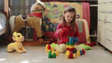 Sevimli küçük kız evde oyuncak bloklarıyla oynuyor.