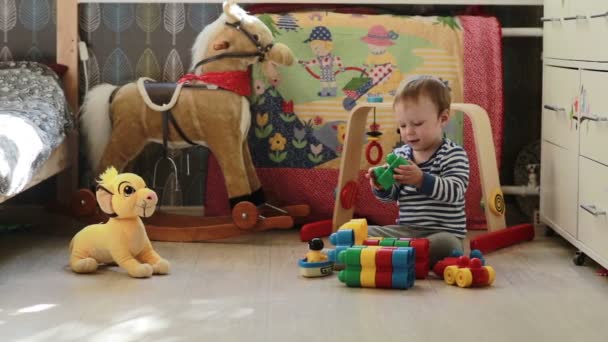 Маленький милый мальчик играет с игрушками в комнате — стоковое видео