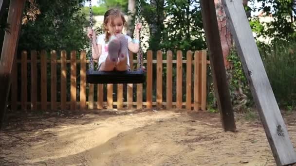 Menina bonito em um balanço no parque — Vídeo de Stock