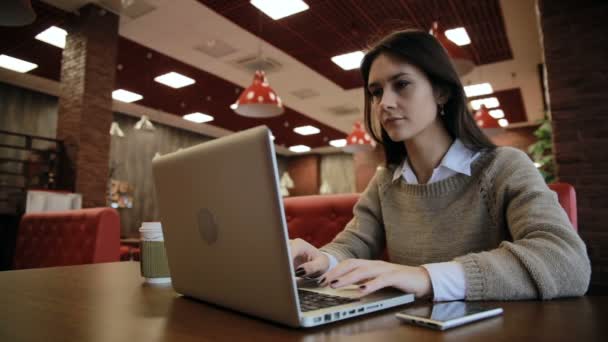 Mujer trabajando en la computadora portátil moderna en la cafetería — Vídeos de Stock