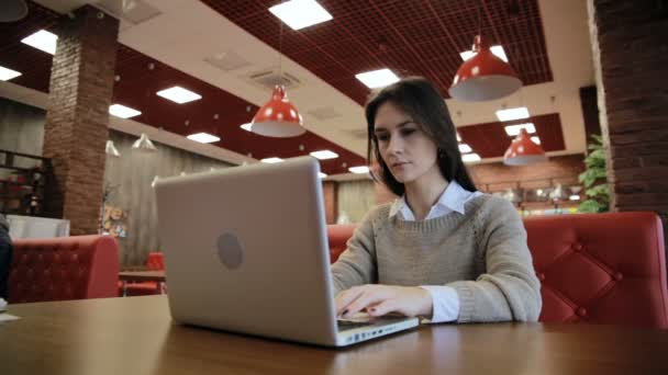 Mujer trabajando en la computadora portátil moderna en la cafetería — Vídeos de Stock