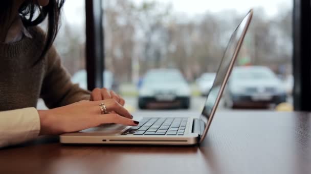 Женские руки работают над ноутбуком в кафе. скольжение влево — стоковое видео