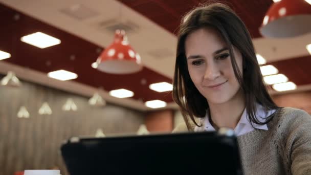 Mujer que utiliza la pantalla táctil de la tableta en la cafetería — Vídeo de stock