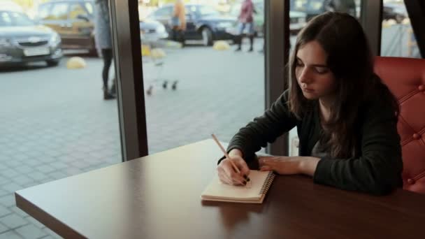 Studente adolescente fa schizzi in notebook in caffè — Video Stock