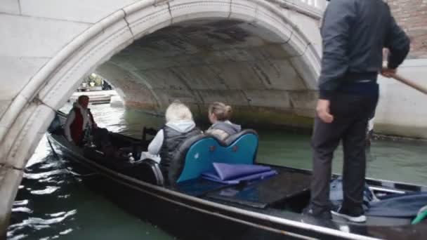 Benátky, Itálie - září 2013: Tě gondola přejde jeho gondola pod mostem na kanále — Stock video