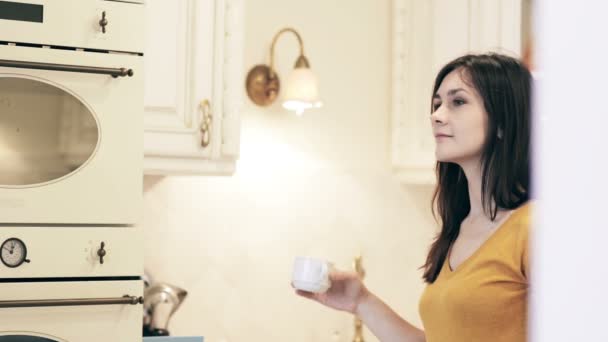 Mujer disfrutando del café de la mañana en una cocina luminosa — Vídeo de stock