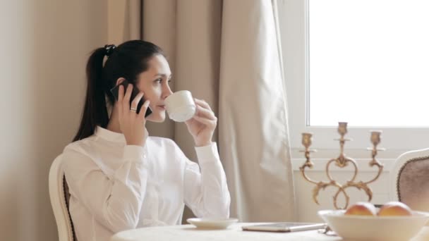 Mujer bebiendo café y utiliza su teléfono inteligente — Vídeos de Stock