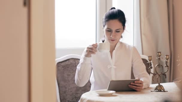 Женщина с планшетом и пить кофе за столом — стоковое видео